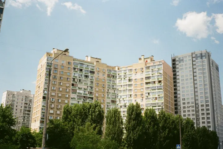 Многоэтажки за деревьями под голубым небом