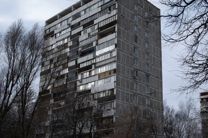 Панельная шестнадцатиэтажка среди голых деревьев